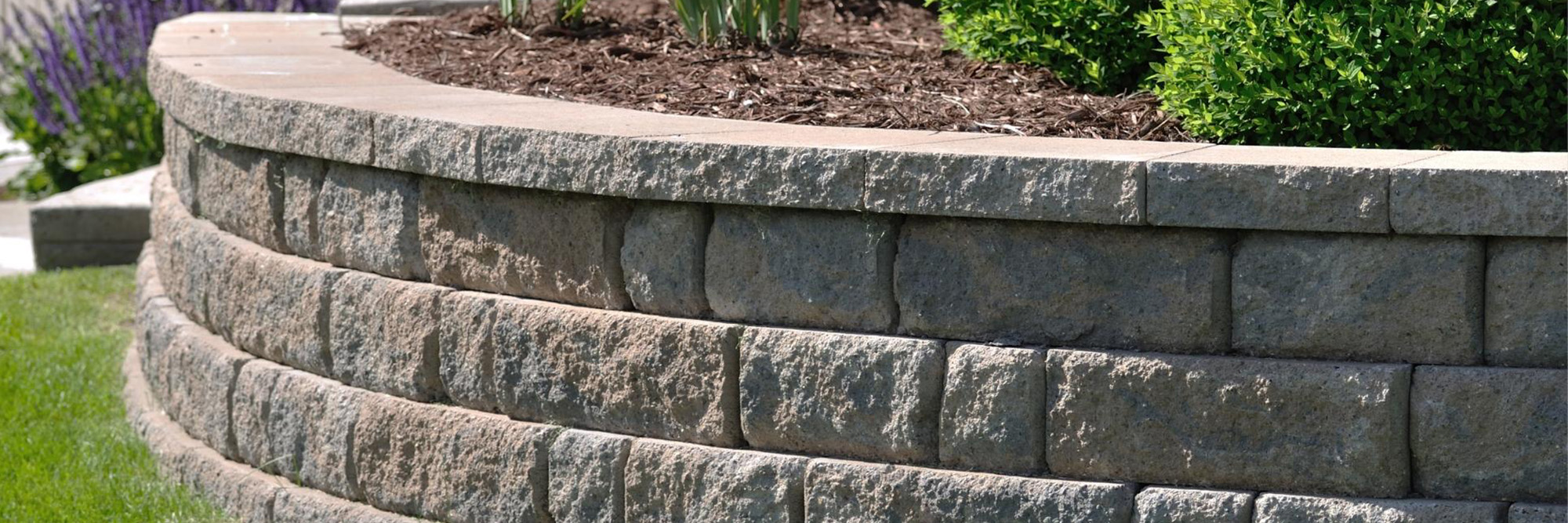 a retaining wall made of blocks in a front yard next to grass
